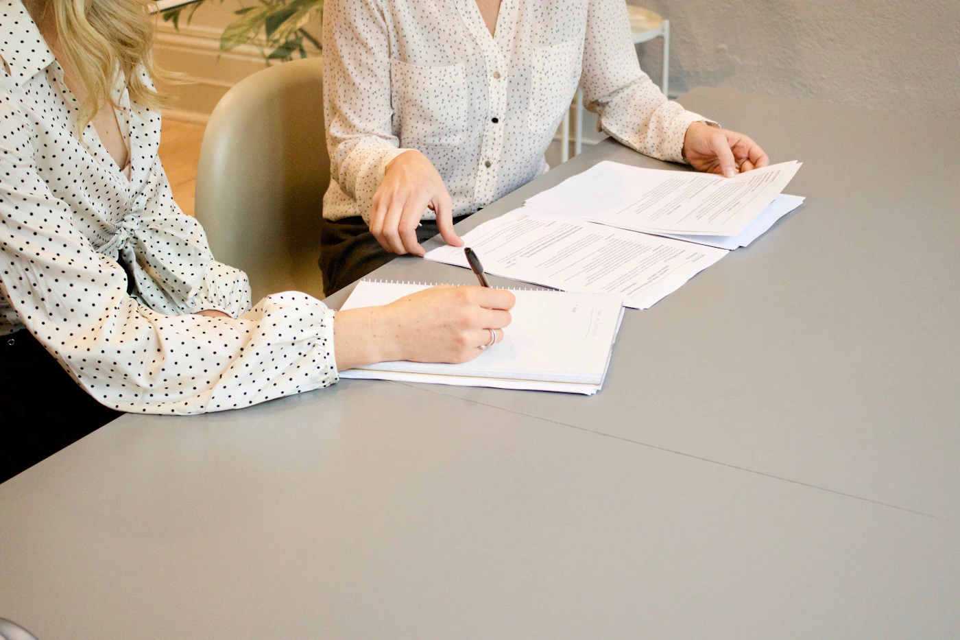 A woman signing a printed document while another person looks on