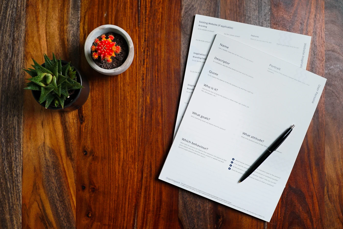 Printed papers and a pen on a wooden table