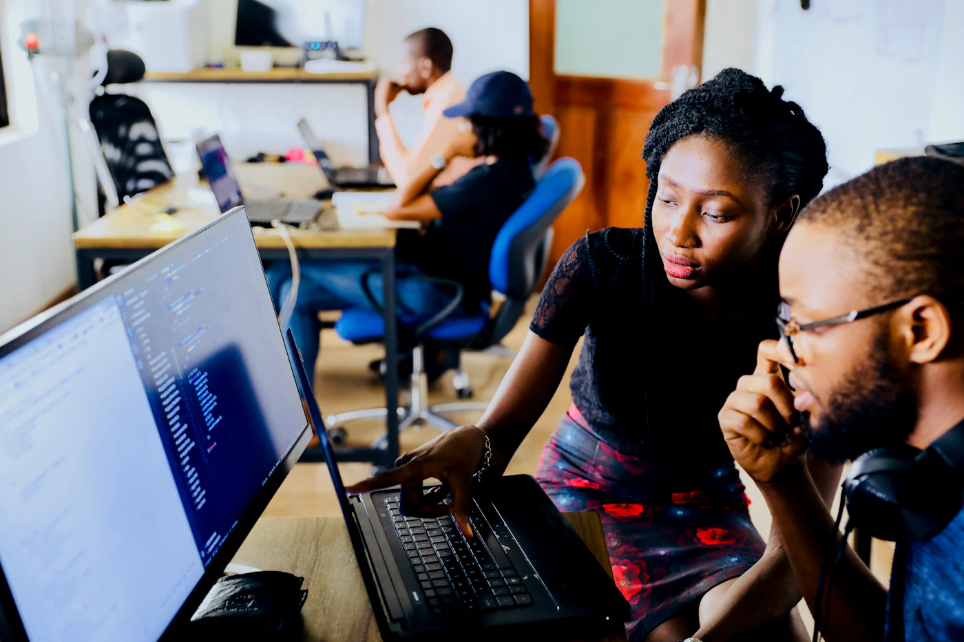 A woman and a man looking at code on a monitor together
