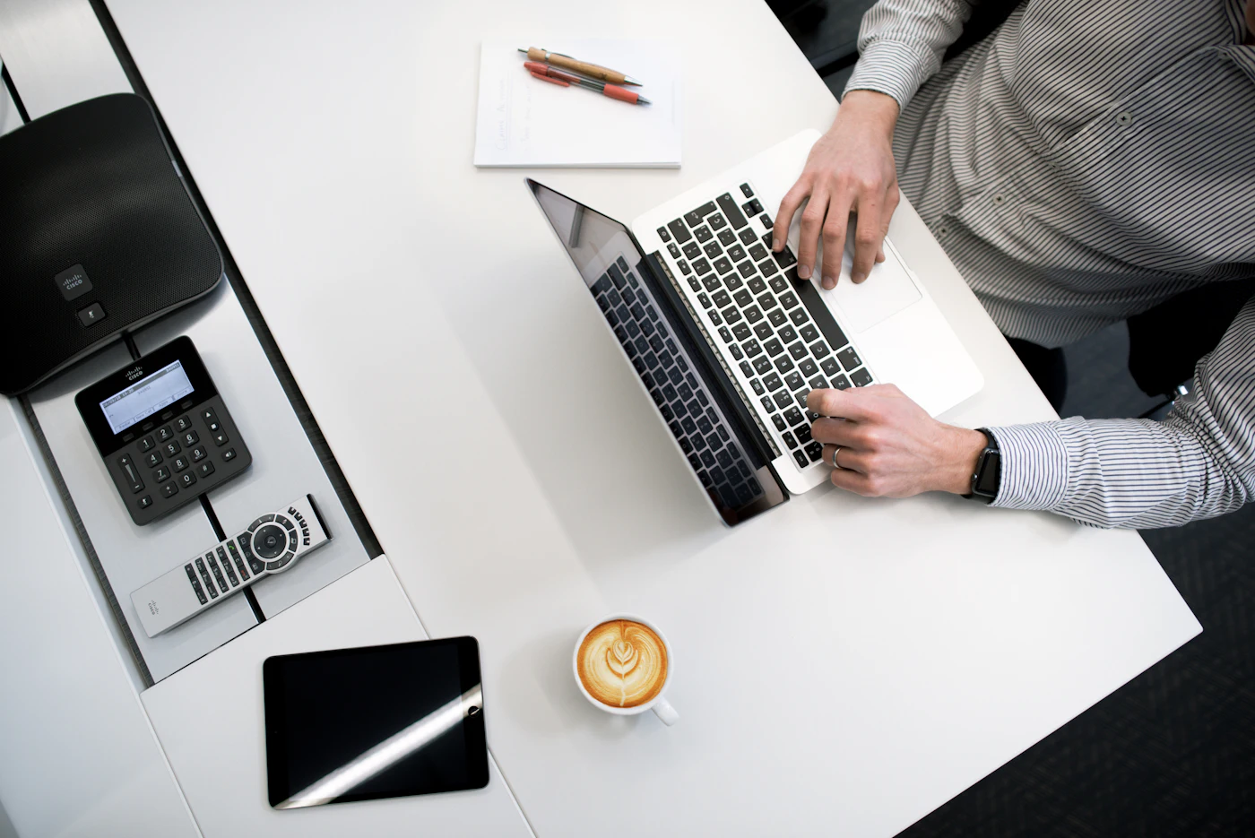 Overhead view of a person using a laptop on a white wooden table